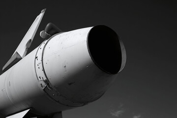 Obraz premium Detailed view of a military missile with a large nozzle against a dramatic sky.
