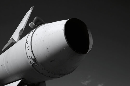 Detailed view of a military missile with a large nozzle against a dramatic sky.
