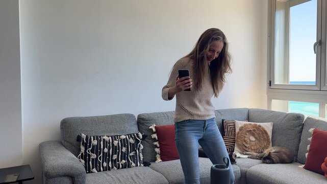 Mujer encendiendo altavoz con m&oacute;vil y bailando