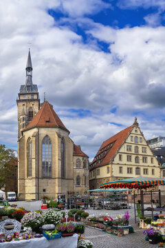 View of Schillerplatz square with Stiftskirche in Stuttgart, Germany. Historical church and flower market under cloudy sky