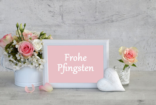 Gru&szlig;karte Frohe Pfingsten: Stillleben mit wei&szlig;em Herz,Rosen und  Schriftzug Frohe Pfingsten.
