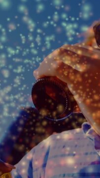 Vertical video: Hands prying cap and sipping brown bottle, gold dust sparkling over social beverage