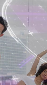 Vertical video: Woman doing side-bend and raising, causing light streaks while man echoing fitness