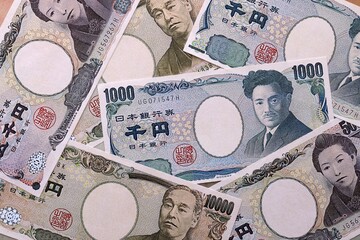 Japanese yen money bills pile on table. Japan banknotes of JPY currency close up. © Larysa