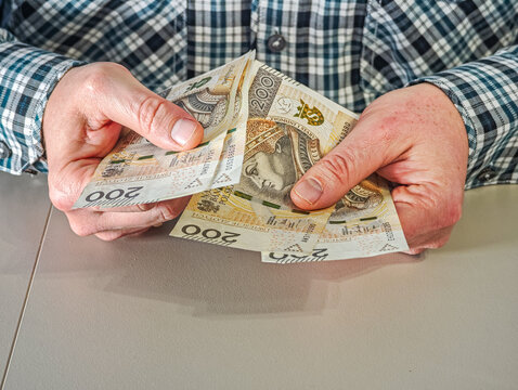 Close up of businessman hands holding stack of Polish Zloty paper money for commercial transaction