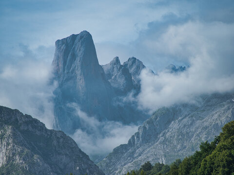 Naranjo de Bulnes in Clouds and Mist - Dramatic vertical view of the iconic Naranjo de Bulnes (Picu Urriellu) peak in the Picos de Europa mountain range, partially obscured by low clouds and mist.