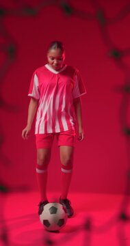 Vertical video: Woman in red kit placing soccer ball at feet juggling right foot training in studio