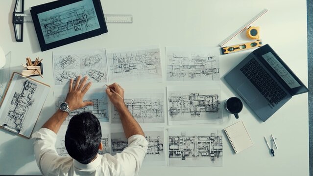 Top down aerial view of architect engineer placing building blueprint on table while checking and choosing project plan. Interior designer select architectural plan from meeting table. Alimentation.