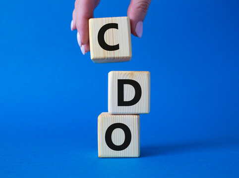 CDO - Collateralized Debt Obligation symbol. Wooden cubes with word CDO. Beautiful blue background. Businessman hand. Business and Collateralized Debt Obligation concept. Copy space.