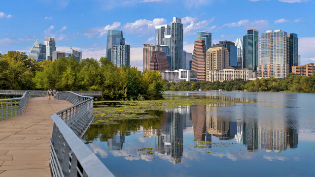 Lake Boardwalk - A panoramic view of the boardwalk of Ann and Roy Butler Hike-and-Bike Trail at Lady Bird Lake, with modern skyscrapers towering in background, on a sunny Autumn day. Austin, Texas, US