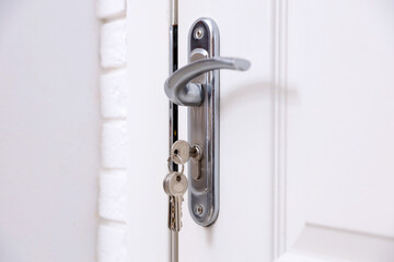 Fototapeta premium Door with keys and metal handle indoors, closeup