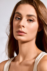 Obraz premium Elegant young woman exudes chic beauty with a serene expression in a soft lit setting.