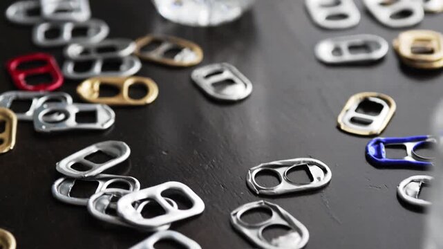 Many colorful aluminum soda can pull tabs lying on a table
