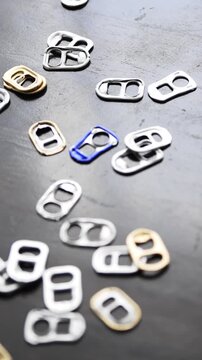Many colorful aluminum soda can pull tabs lying on a table
