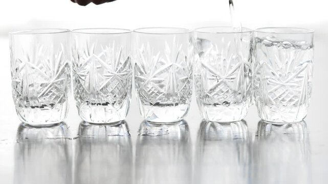 Five transparent glass shots in a row, bartender pouring clear alcohol with pouring sound
