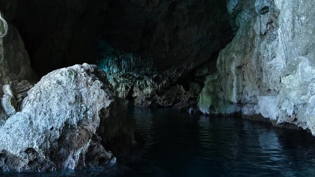 Turkiye, Belek, 27.07.2025 Blue water flows inside a hidden sea cave in Turkey. Natural limestone grotto with dark rocky walls. Beautiful coastal landscape for summer vacation adventure.