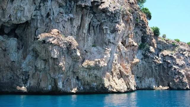 Turkiye, Belek, 27.07.2025 Steep rocky cliff rising from vivid blue Mediterranean sea in Turkey. Coastal landscape during sunny summer holiday. Nature travel scenery for editorial vacation.