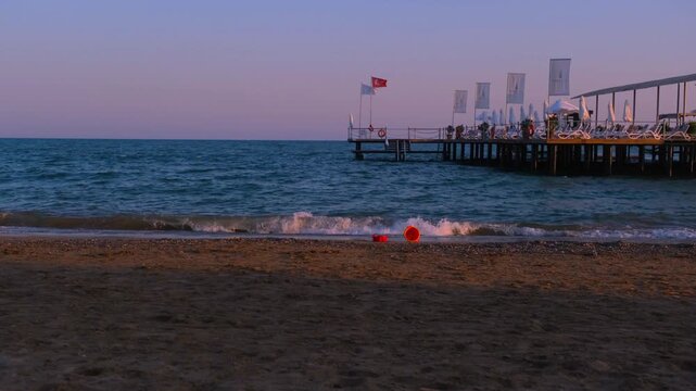 Turkiye, Belek, 27.07.2025 Scenic seaside in Turkey at sunset with long wooden pier and red floating buoy. Vacation resort shoreline with peaceful waves and horizon during holiday travel.