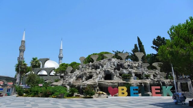 City square with mosque and artificial waterfall in Belek. Tourist landmark in Turkey for summer vacation. Beautiful architecture and scenery for travel editorial.