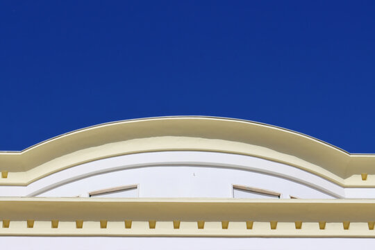 Elegant architectural detail with a curved classical facade against a clear deep blue sky, ideal for urban design, travel themes, and building exterior concepts.