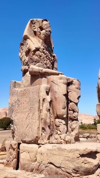 Vertical panning shot moving left across the Colossi of Memnon statues in Luxor, Egypt. Ancient Egypt travel concept.