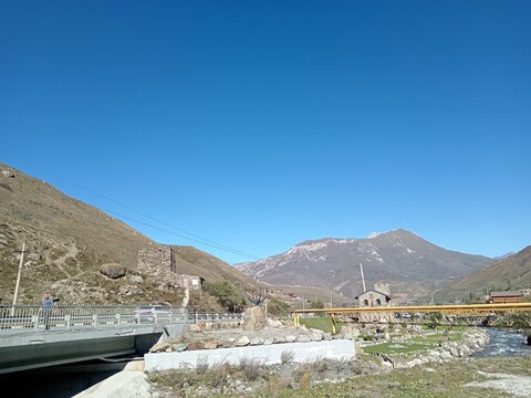Kurtatinsky Gorge village of Hidikus, North Ossetia, Russia, bright summer day. Traditional Ossetian architecture with stone buildings lining a narrow mountain road
