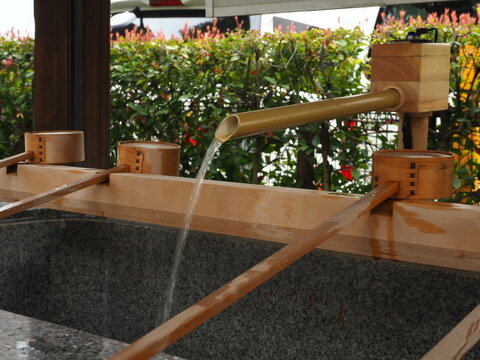 Japanese shrine purification basin with flowing water and bamboo ladle - Temizuya water basin at a Japanese shrine with flowing water and bamboo ladle, used for ritual purification in Shinto tradition