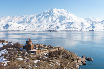 View of Akdamar Island with Holy Cross Church, Lake Van and snow-covered mountains, highlighting cultural heritage and winter landscape in eastern Türkiye © osmanmaasoglu