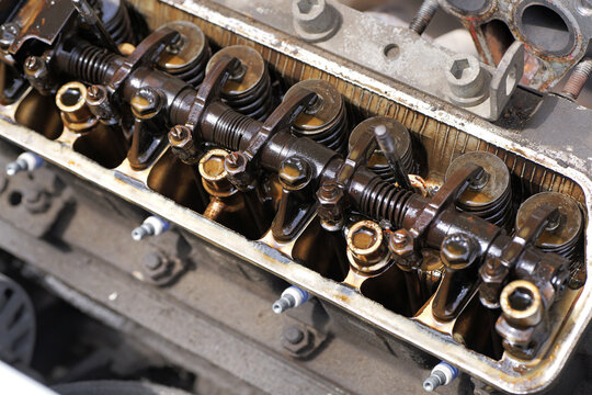 Close-up of an open engine with removed valve cover showing rocker arms and heavy oil sludge deposits, indicating wear and maintenance issues in a four-cylinder engine. 2026