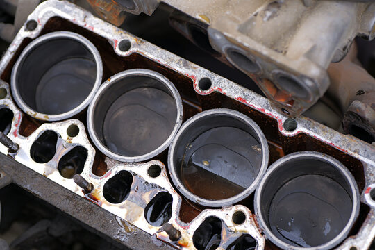 Four-cylinder engine block with removed cylinder head showing pistons, fluid contamination, and gasket residue, indicating maintenance and repair condition. 2026