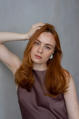 Fototapeta premium Portrait of young redhead woman with freckles in studio. Sensual expressive happy woman