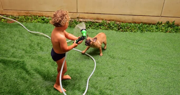 Young child and lively puppy engage in water experiments using hand sprinkler. Joy and laughter of their interaction fill air, creating atmosphere of excitement and freedom.