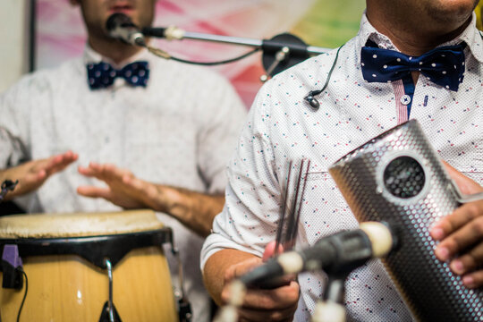 Musicians playing conga and guiro instruments in a band performance