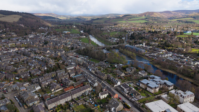 Panoramic view of the River Tweed flowing through Peebles, featuring historic stone bridges and traditional architecture. Scenic landscape of the Scottish Borders town with focus on the riverside, arc