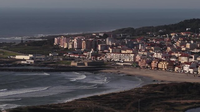 Aerial view of the coastal cityscape with sandy beach meeting the ocean, creating contrast with the buildings, Vila Praia de Ancora, Portugal.