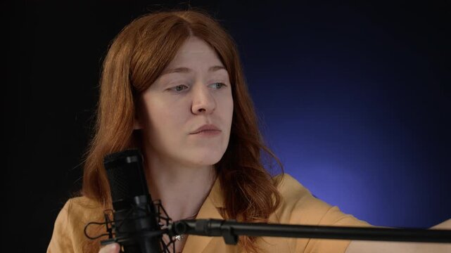 Close up of young woman chewing bubble gum while setting professional microphone before podcast in studio