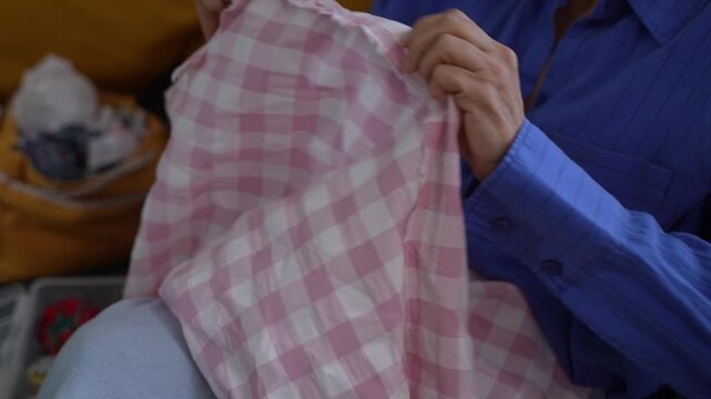 Elderly woman hand sewing plaid fabric