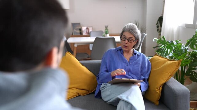 Senior female psychologist counseling young male patient