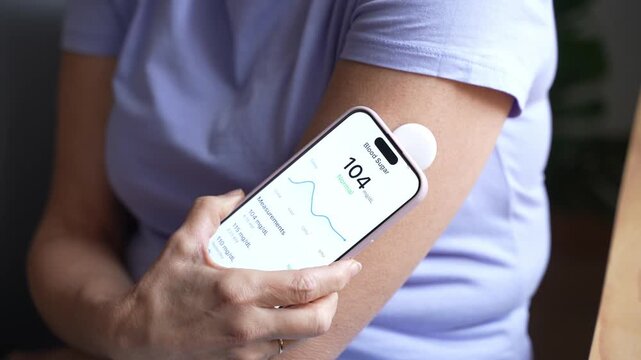 Woman scanning continuous glucose monitor with smartphone