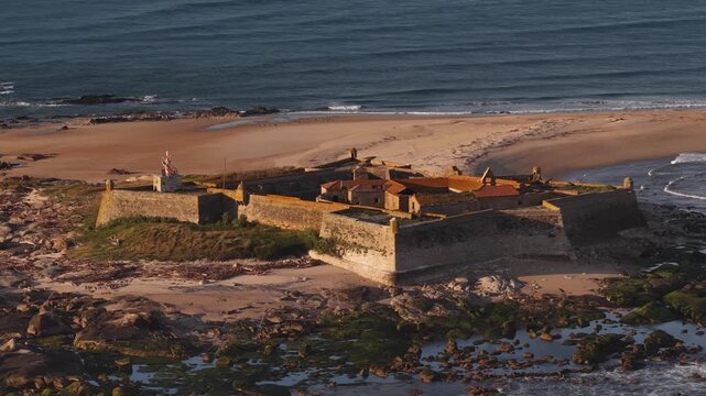 Aerial view of Forte de Insua, a historic fort surrounded by beach, ocean, and rocks, creating a striking contrast of textures, Moledo, Portugal.