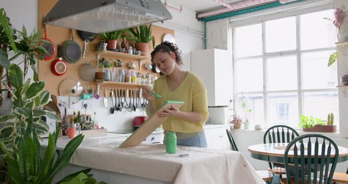 Young Woman Painting a shelf in her cosy Kitchen