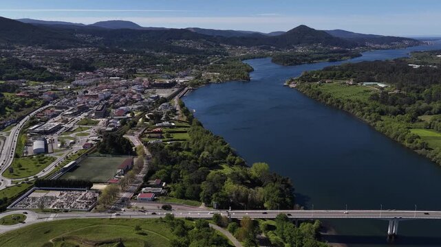 Aerial view of the Minho River flowing through lush greenery, bisecting the landscape, with a bridge spanning its waters, Vila Nova de Cerveira, Portugal.