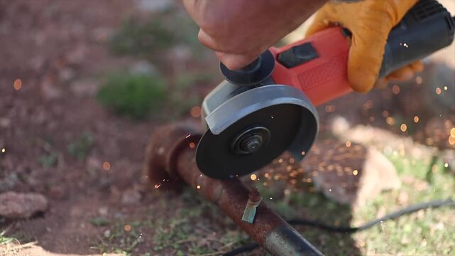 Man is cutting a metal list by angle grinder saw.
