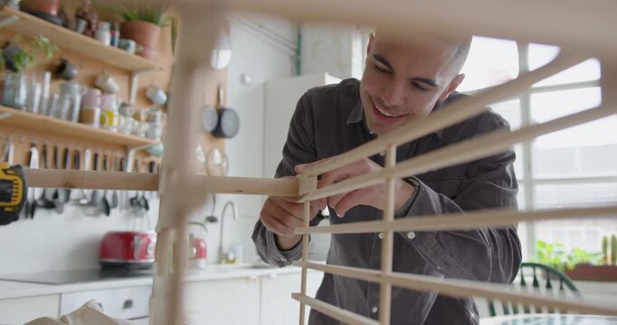 Young Adult Male Assembling a piece of flat pack furniture at home