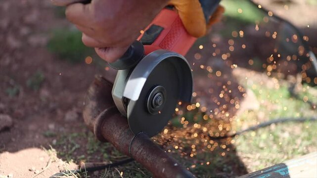 Man is cutting a metal list by angle grinder saw.
