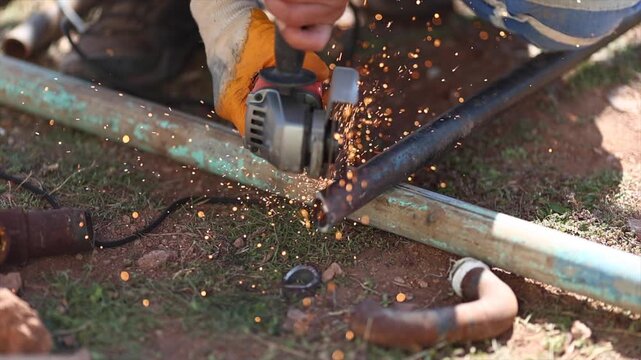 Man is cutting a metal list by angle grinder saw.