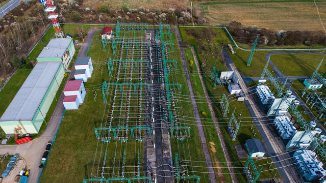 Aerial view of a complex network of power lines and industrial buildings contrasts with the surrounding green fields, Praha-Seberov, Hlavni mesto Praha, Czechia.
