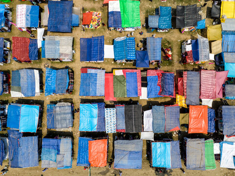 Aerial view of colorful makeshift shelters create a patchwork of textures and tones against the bare earth, Charmonai, Barisal Division, Bangladesh.