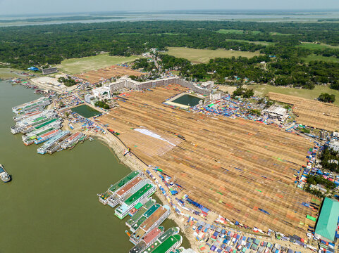 Aerial view of the vast landscape where the brown hues of drying goods meet the shimmering water and the green forest, Charmonai, Barisal Division, Bangladesh.