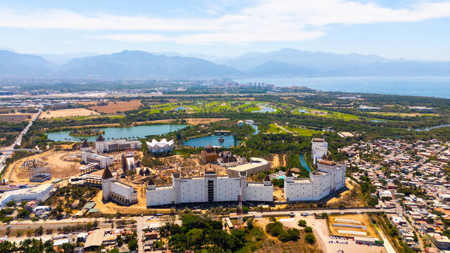 Aerial view of an elaborate castle-like structure nestled amidst a vibrant landscape of green fields and winding waterways, Riviera Nayarit, Mexico